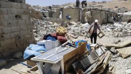 A Syrian man gathers his belongings as workers demolish cement block shelters at a refugee camp in the northeastern Lebanese town of Arsal, in the Bekaa valley 