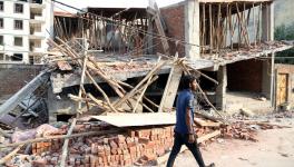 A man walks past demolished structure after a demolition drive