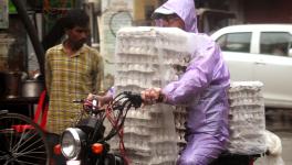 A vendor carries the pile of eggs covered in the plastic sheets on his bike