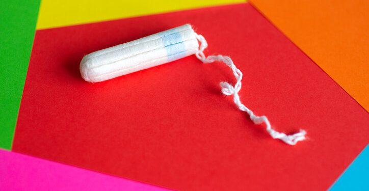 Feminine hygiene tampon on red, pink, orange background, close up 