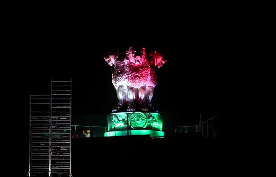 National Emblem cast on the roof of the New Parliament Building, lit up in tricolour on the eve of 76th Independence Day, in New Delhi on Sunday.